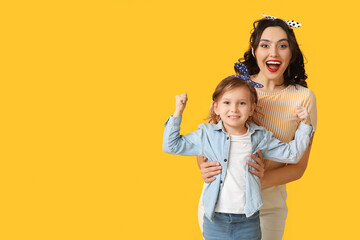 Beautiful pin-up woman and her daughter showing muscles on yellow background