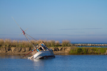 A Capsized Fishing Boat Leaning Sideways in the Mud at Moss Beach Landing, Monterey Bay,...