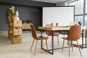 Interior of light modern conference hall with table, screen board and armchairs