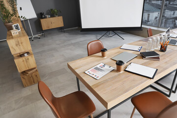 Wooden table, armchairs and stationery prepared for business meeting in modern conference hall