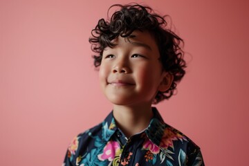 Portrait of a little boy in a shirt on a pink background