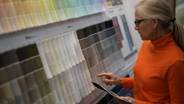 Closeup of mature woman looking at paint chips in a hardware store. Concept of shopping experience for home improvement.