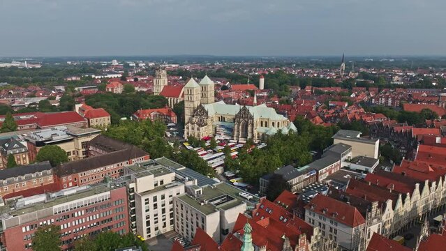 An aerial drone shot of St. Paulus Dom, also known as M&uuml;nster Cathedral, on Domplatz in M&uuml;nster on a sunny day. It is a central and culturally significant area of central M&uuml;nster, Germany. Busy Market