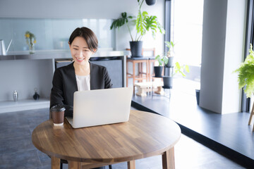 笑顔でパソコンの仕事をするスーツを着た女性のビジネスシーン 広角