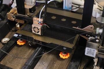 The 3D printer is performing the 3D printing process of children made from black plastic, the 3D...