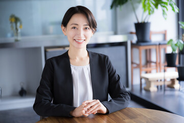 Business scene of a woman in a suit, smiling and talking, looking at the camera Image of a...