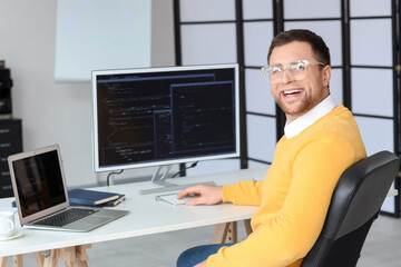 Portrait of male programmer working with computer and laptop in office
