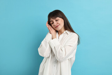 Woman in pyjama sleeping on light blue background