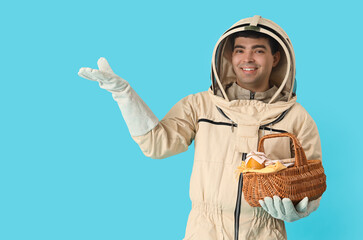 Male beekeeper with basket of honey on blue background - Powered by Adobe