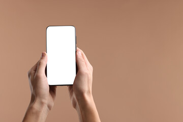 Man holding smartphone with blank screen on beige background, closeup. Mockup for design