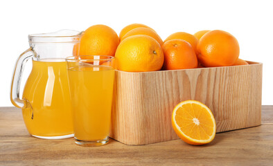 Fresh oranges in crate and juice on wooden table against white background