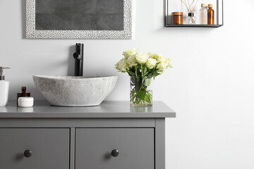 Vase with beautiful white roses and toiletries near sink in bathroom, space for text