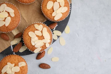 Rolgordijnen Muffins with fresh almond flakes and nuts on grey table, flat lay. Space for text © New Africa
