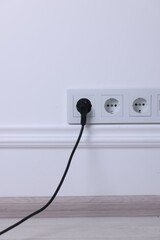 Power sockets and electric plug on white wall