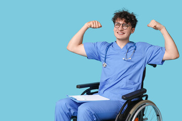 Young doctor on wheelchair with stethoscope and clipboard showing strength gesture on blue...
