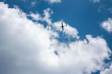 Fototapeta na wymiar A stunning aerial view of a small private airplane gracefully soaring through fluffy white clouds in a clear blue sky on a sunny day, capturing the beauty of nature and the freedom of flight.