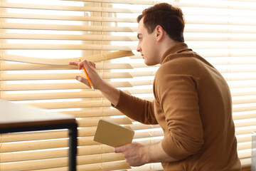 Male spy with notebook looking out window in office