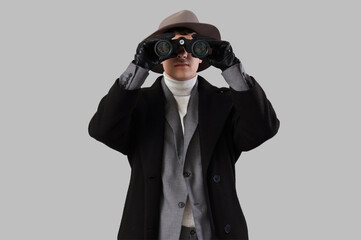 Male spy looking through binoculars on light background