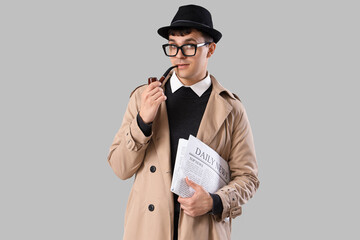 Male spy with smoking pipe and newspaper on light background