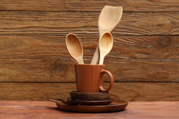 Brown clean tableware and cup with spoons on table against wooden background