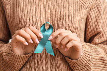 Young woman with teal ribbon on white background, closeup. Sexual Assault Awareness Month