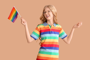Beautiful young happy woman with LGBT flag on beige background