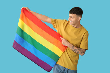 Handsome young happy man with LGBT flags on blue background