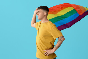 Handsome young happy man with LGBT flags on blue background