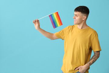 Handsome young happy man with LGBT flags on blue background