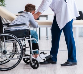 Young male doctor pediatrist and boy in wheel-chair - 782616923