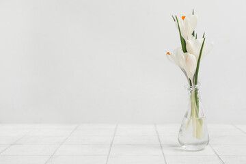 Glass vase with beautiful crocus flowers on white tile table