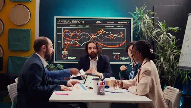 Startup team evaluating infographics data in an executive meeting, corporate restructuring or organizational changes. Adapting the organization to evolving market conditions. Camera B.