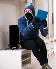 Man burglar stealing tv set from house - 782618306