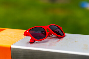 Red Glasses Resting on a Metal Surface, Adorned with Glistening Raindrops
