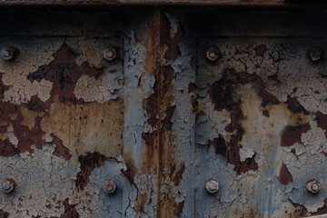 Close view backdrop of rusted metal with peeling paint, patina of decay and exposure to the...