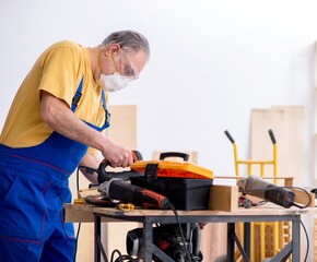 Old male carpenter working in workshop - 782623737