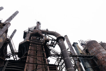 View looking up of rusting derelict steel mill structures against a gray sky in winter, horizontal aspect