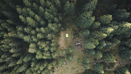 Top down tent at mountain pine forest aerial. Nature autumn landscape. Pavilion camp for tourists rest and recreation. Mountaineering lifestyle. Vacation at Carpathians fir mount, Ukraine, Europe