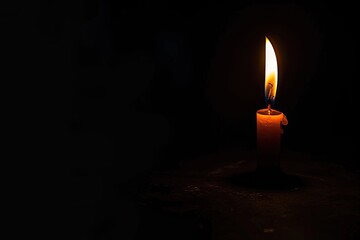 Single candle flame flickering in the vast darkness