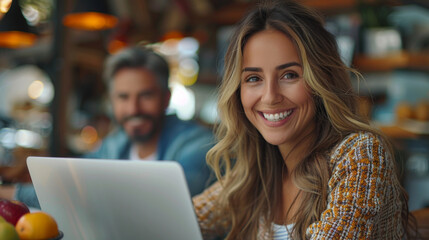 Two Colleagues Working On Laptop in Office. Female Hispanic Help Desk Coordinator Collaborates with White Male Customer Service Agent, They Discuss a Project, Chat, Smile. Teamwork Collaboration