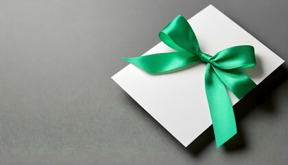 gift card with ribbon on green, blank green gift card with a vibrant black ribbon bow right side, a minimalist grey background with subtle shadowing. 
