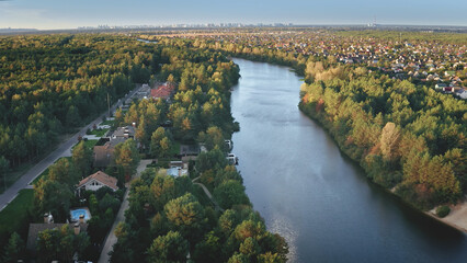 Green forest at river banks aerial. Autumn nobody nature landscape. Cityscape at stream. Downtown buildings. Urban streets with cottages. Cinematic Dnieper, Kiev city, Ukraine, Europe
