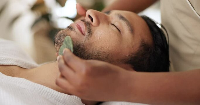 Man, gua sha and face treatment in spa with massage for chronic pain, pressure points or lymphatic drainage. Male person, beautician and hands as jade tool or circulation benefits, skincare or beauty