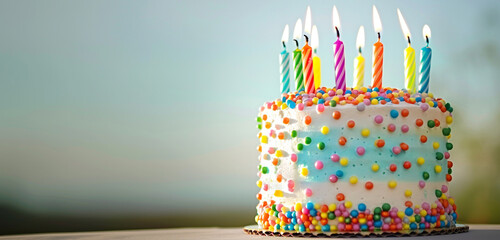 A delightful birthday cake adorned with colorful candles sits proudly on a table against a serene light blue sky background. The HD camera captures the cake's intricate details and vibrant colors