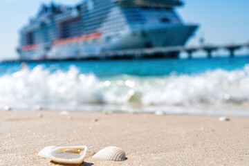 Seashells on the beach in the sand and blurred large cruise ship on the back. Exotic island scene....