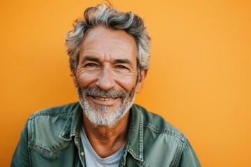 Portrait of a happy senior man smiling and looking at camera against yellow background