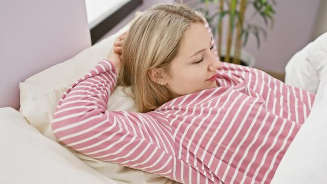 A young woman relaxes in a striped shirt, lying peacefully in her bedroom's comfortable bed, embodying tranquility and domestic leisure.