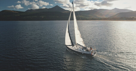 Aerial of sun yacht sail in ocean bay. White boat at open sea. Summer cruise on sailboat at...