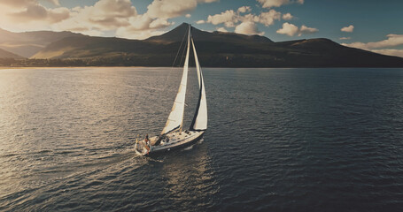Closeup aerial sailboat cruise at sun sea bay. Sunshine reflection at water near mountains ocean...