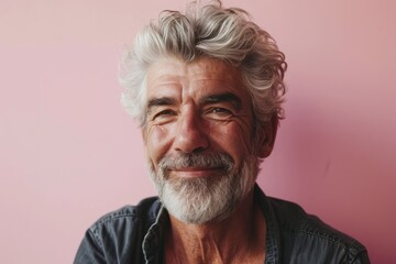 Portrait of happy senior man with grey hair and beard. Isolated on pink background.